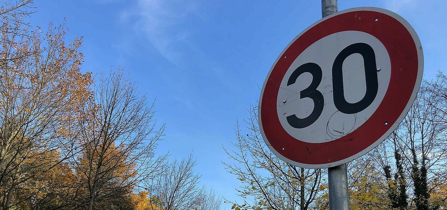 Verkehrsschild Tempo 30 vor blauem Himmel und Bäumen