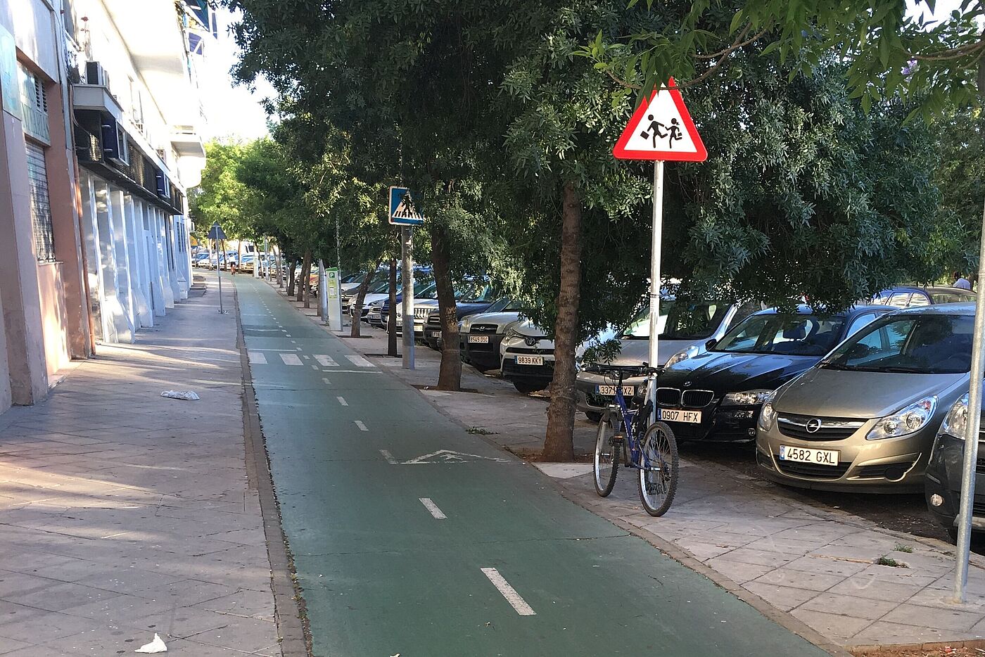 Grün markierter Zweirichtungsradweg zwischen Gehweg und Parksteifen in Sevilla.