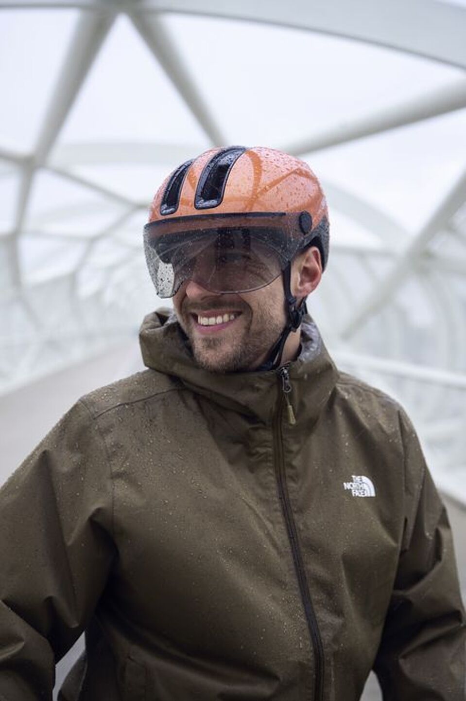 Ein großes Visier am Helm hilft bei Regen. Mann mit Fahrradhelm mit Visier und Regenjacke